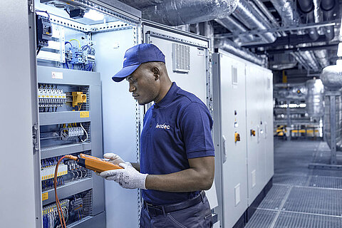 Leadec employee checking control cabinet.