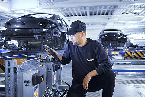 A Leadec employee configures an inverter at a conveyor belt.